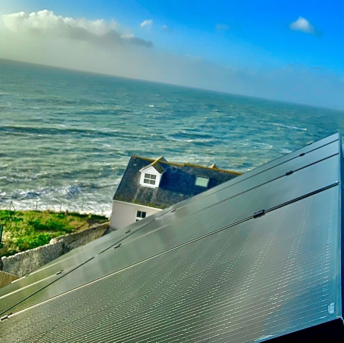 俯瞰大海的独立房屋屋顶上的太阳能电池板